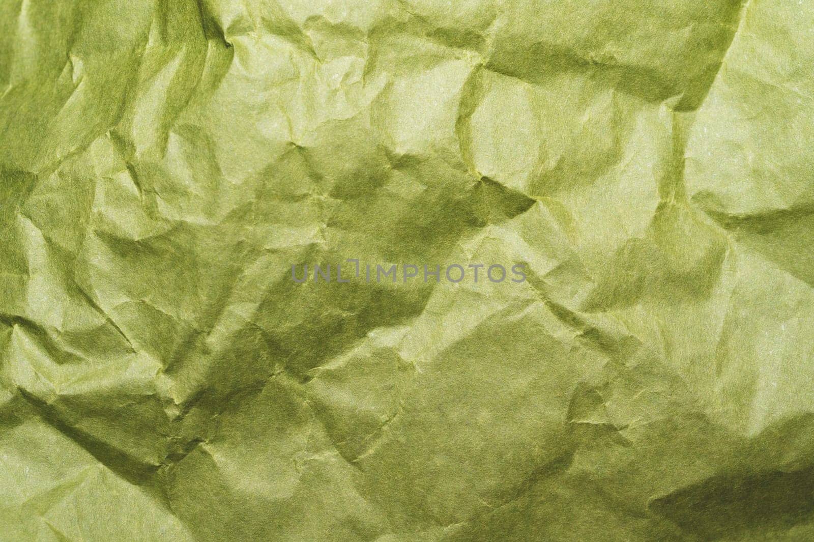 Crumpled green paper close up. creased kraft paper material