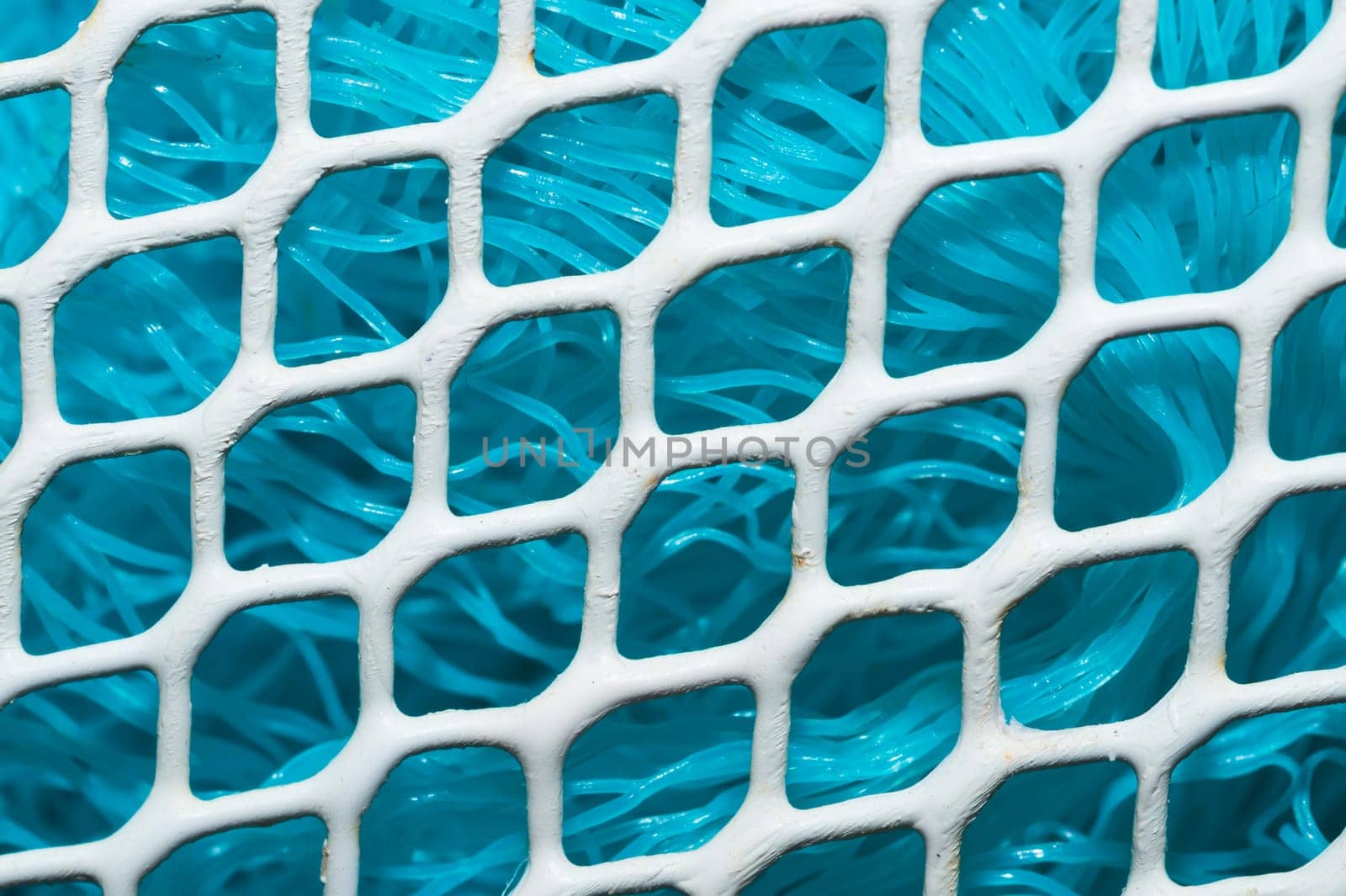 Metal enameled grid. abstract background. blue cloth behind the metallic grate. iron white mesh