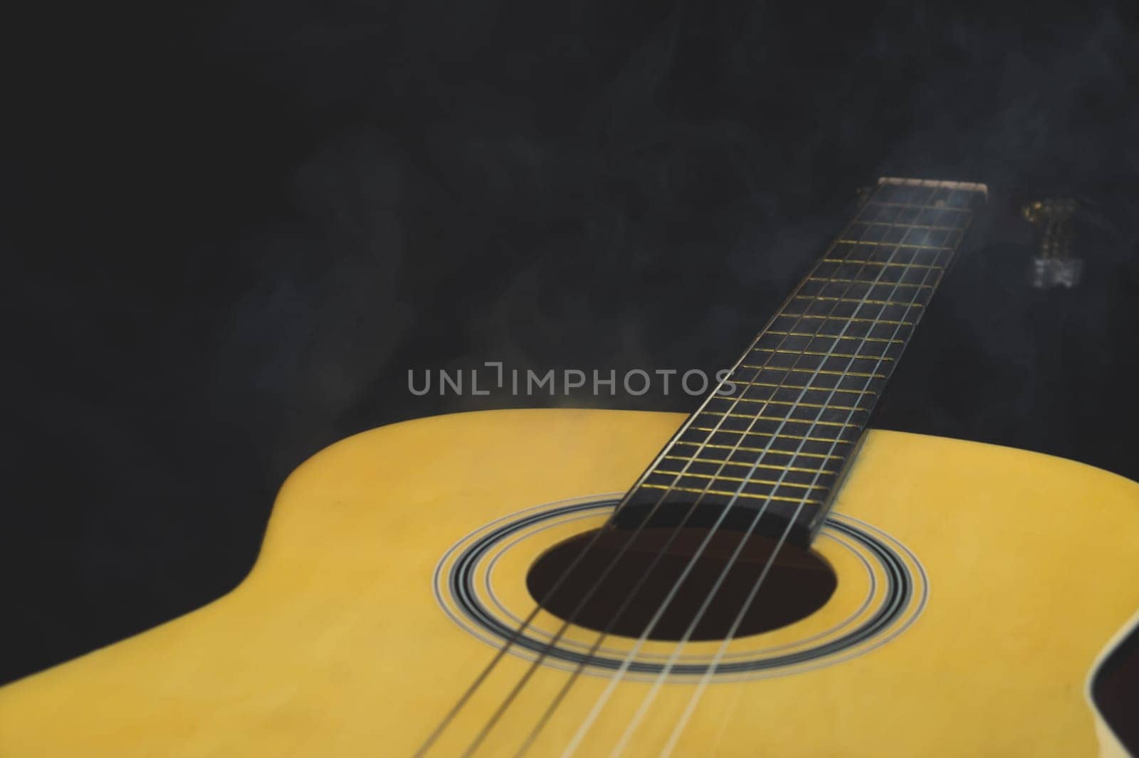 Acoustic guitar in smoke close up. musical instrument. strings on the guitar fretboard