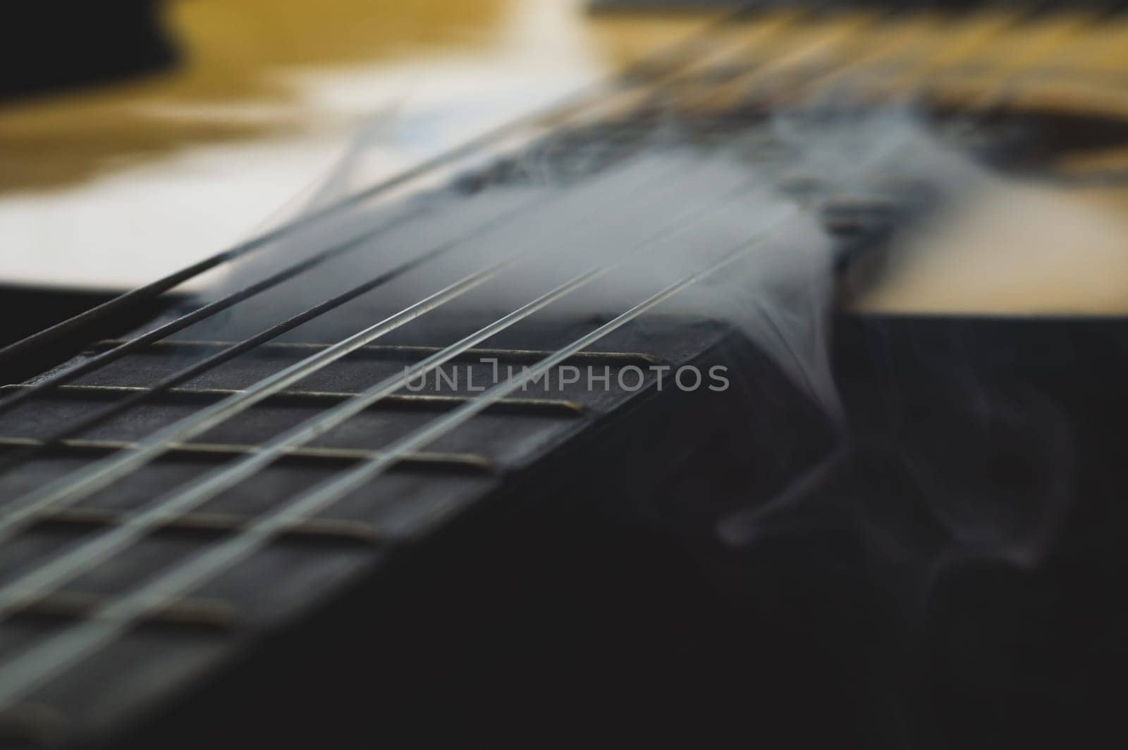 Acoustic guitar in smoke close up. musical instrument. strings on the guitar fretboard