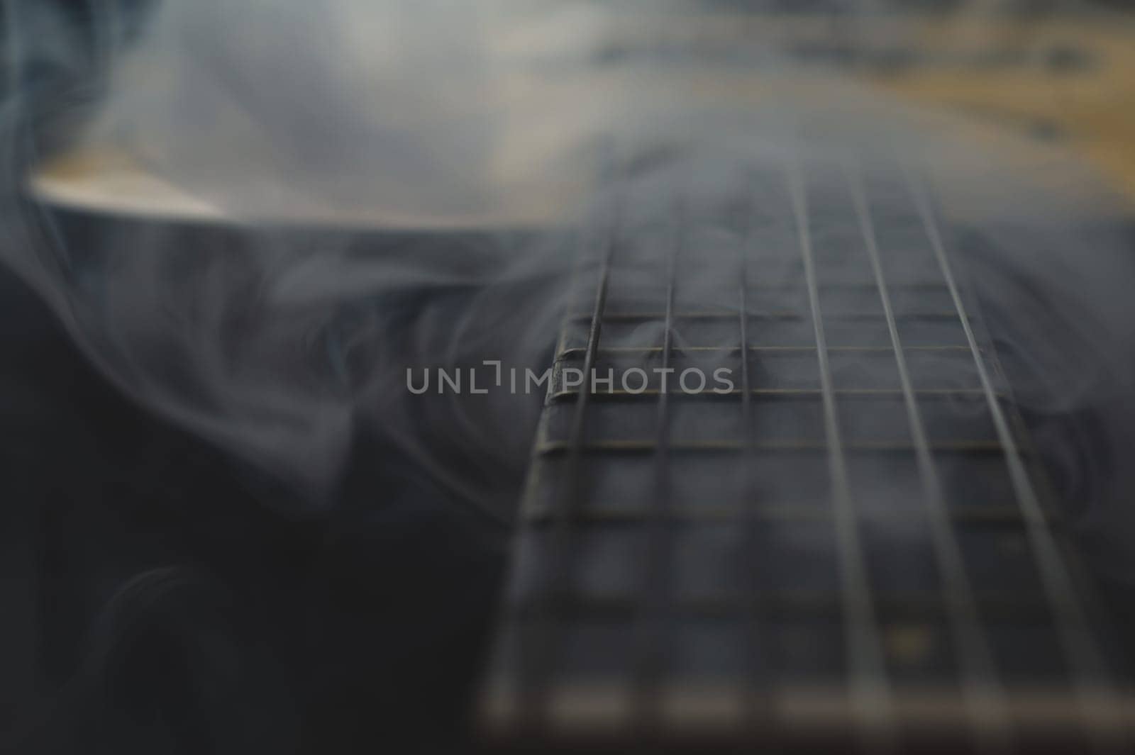Acoustic guitar in smoke close up. musical instrument. strings on the guitar fretboard