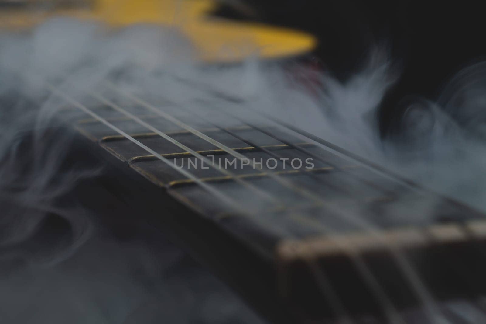 Acoustic guitar in smoke close up. musical instrument. strings on the guitar fretboard