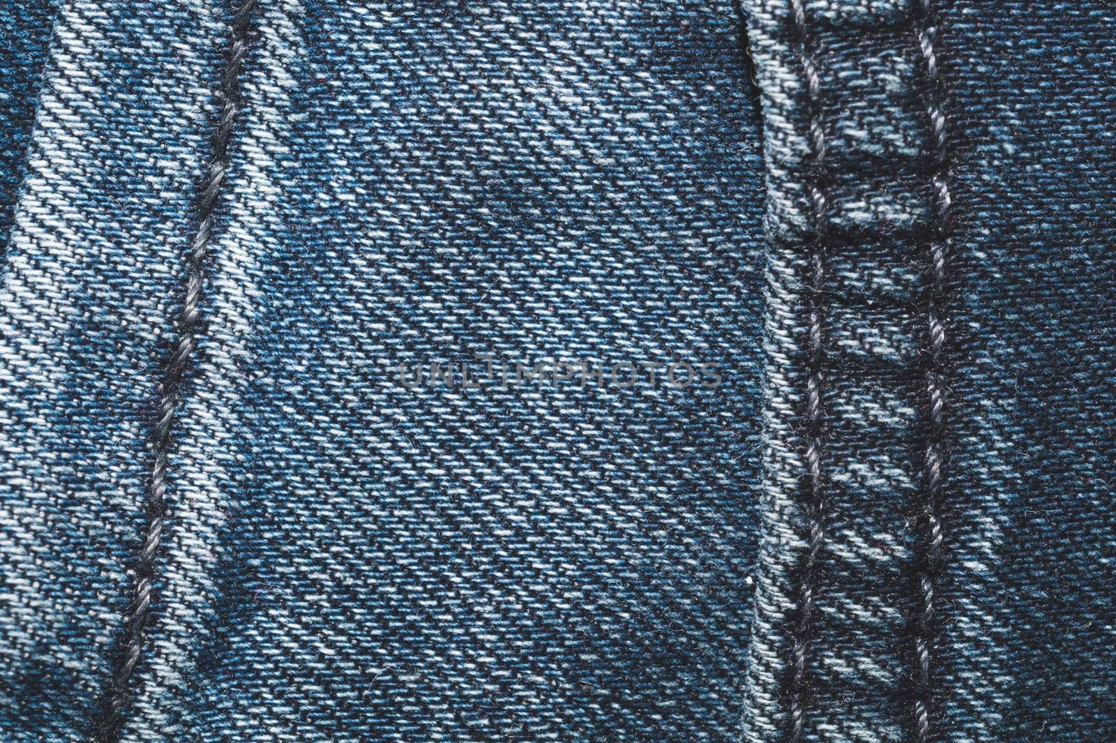 Jeans background with seams. denim texture close up. fabric backdrop with stitches