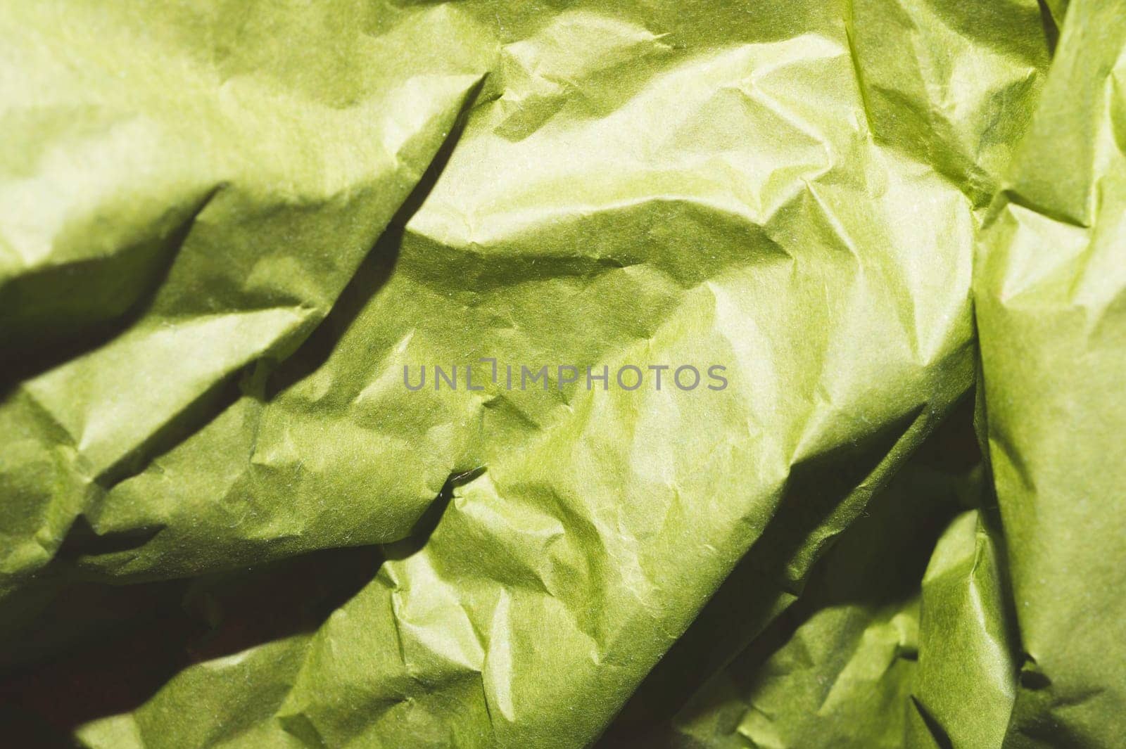Crumpled green paper close up. creased kraft paper material
