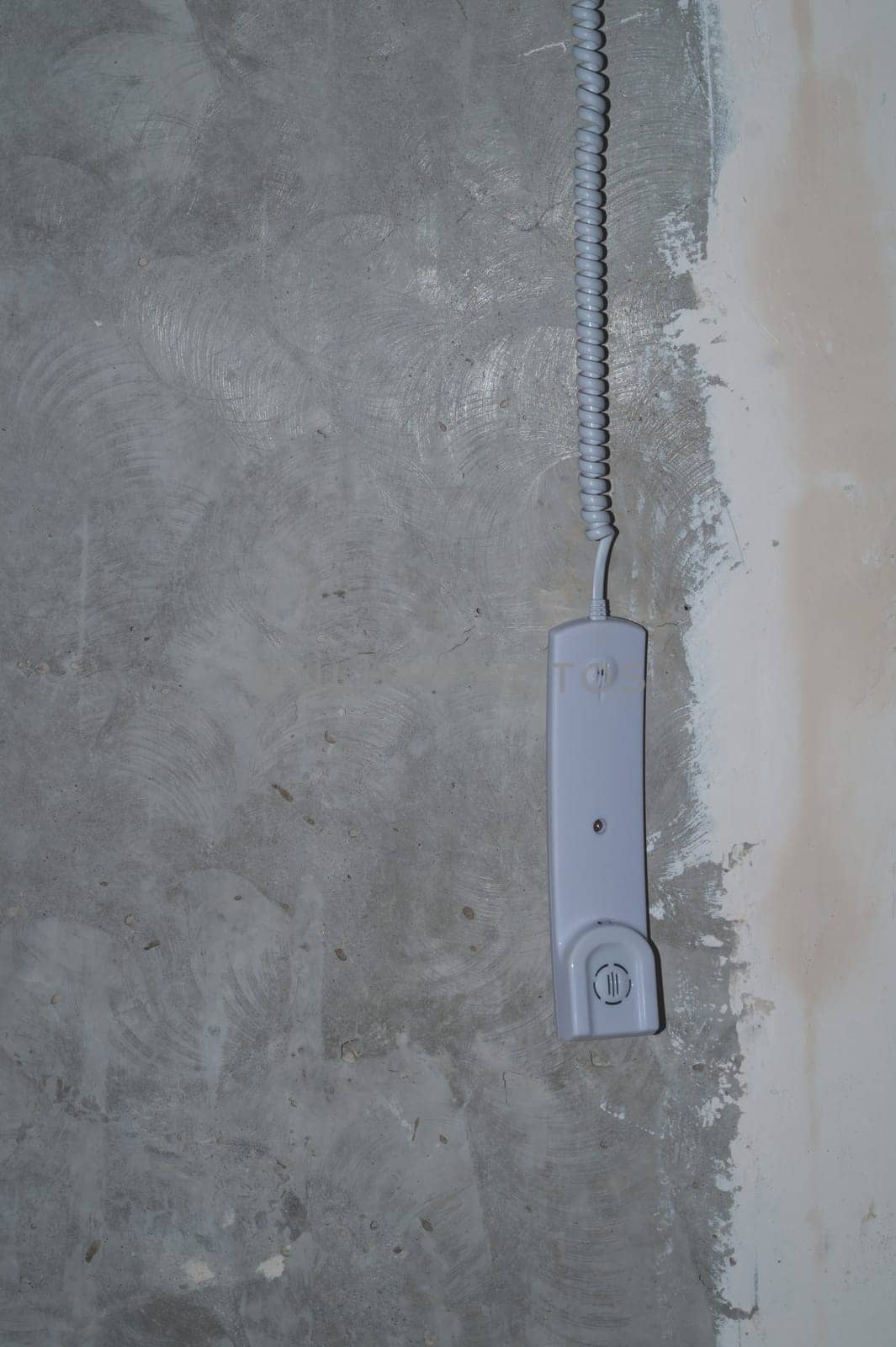 Intercom phone receiver on gray concrete background. handset hanging on the wire close up
