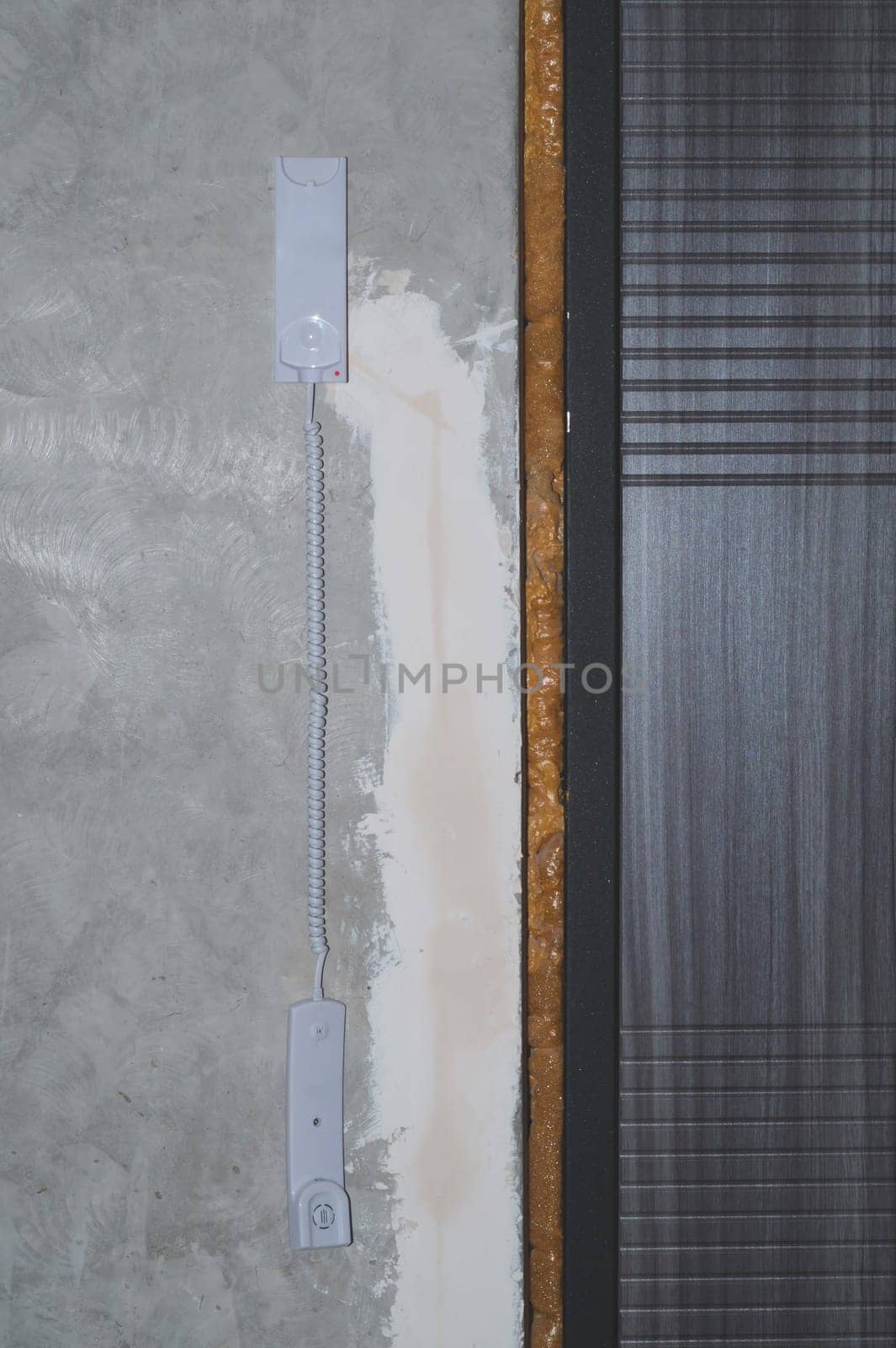 Entrance door and intercom phone receiver on the wall. handset hanging on the gray concrete background close up