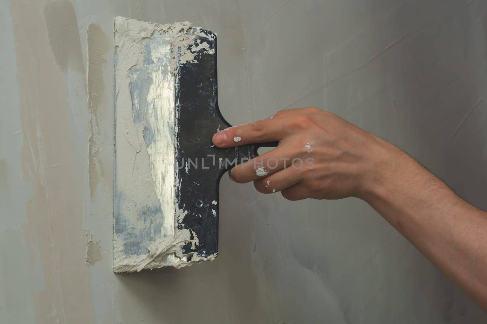 Hand holds construction spatula with putty. trowel with spackling. process of renovation