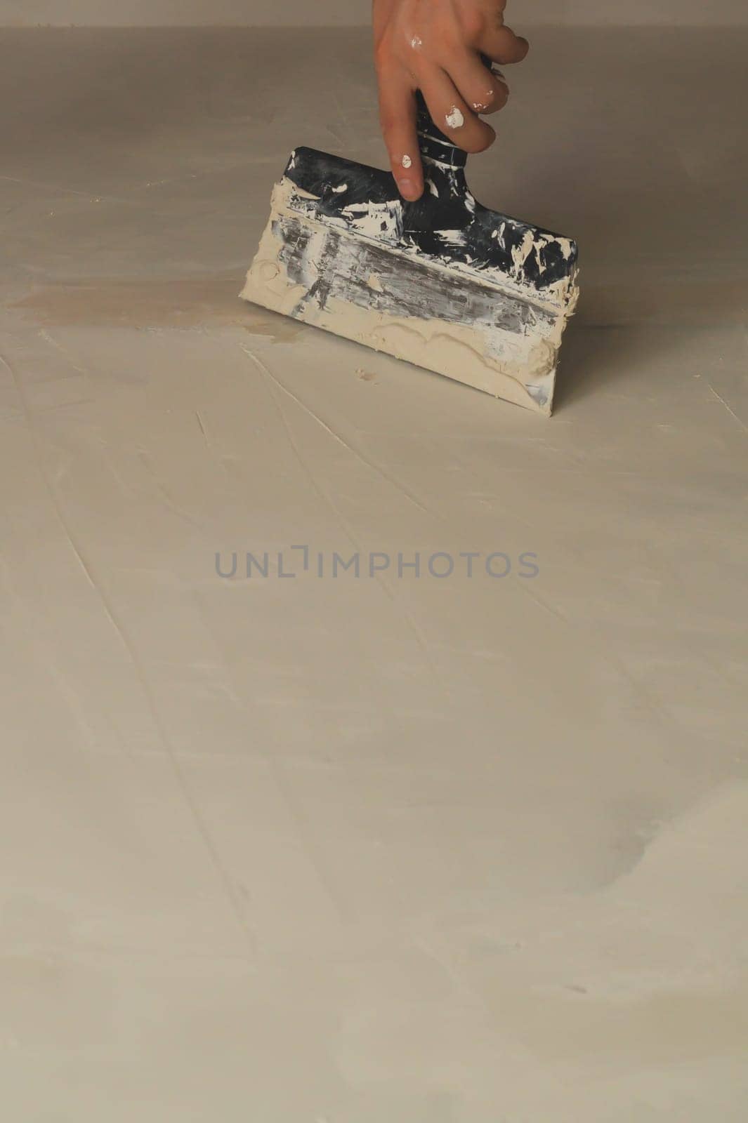 Hand holds construction spatula with putty. trowel with spackling. process of renovation