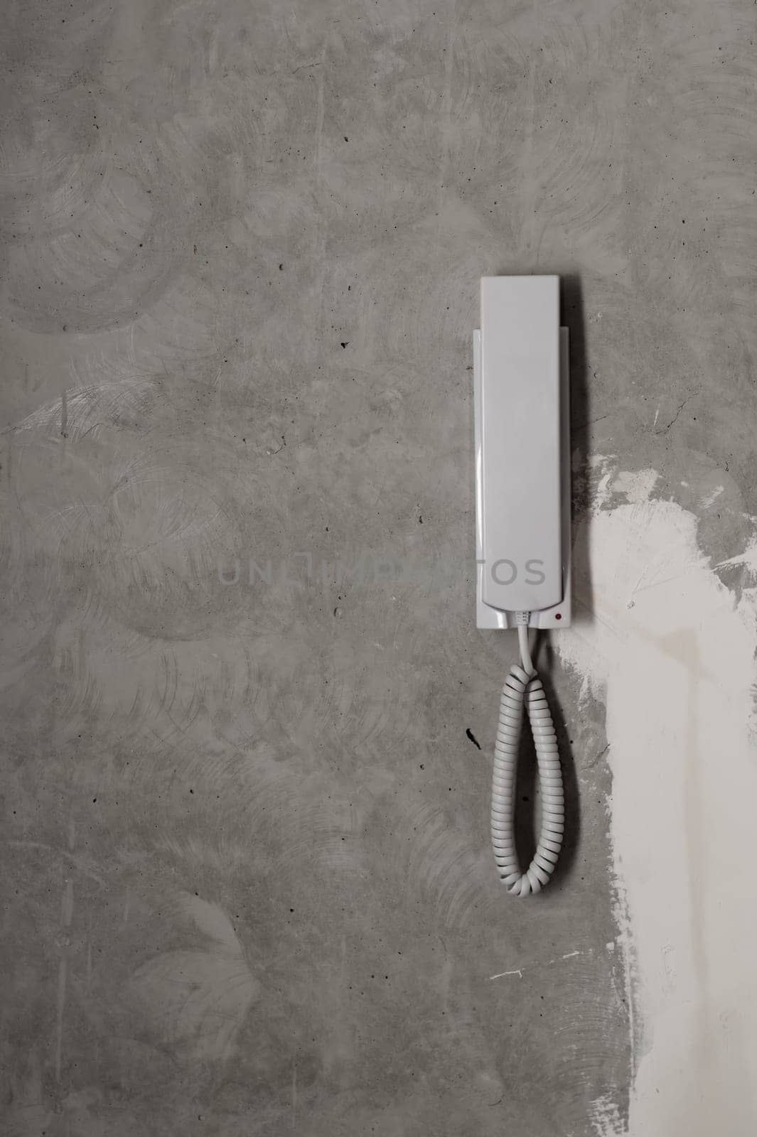 Intercom phone receiver on gray concrete background. handset on the wall close up