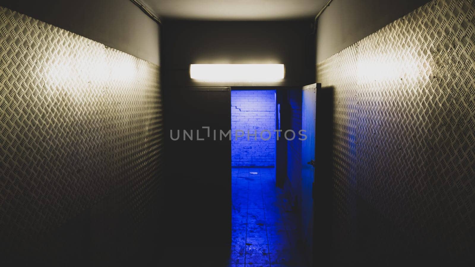 Blue light behind an open door in a mysterious corridor. secret exit