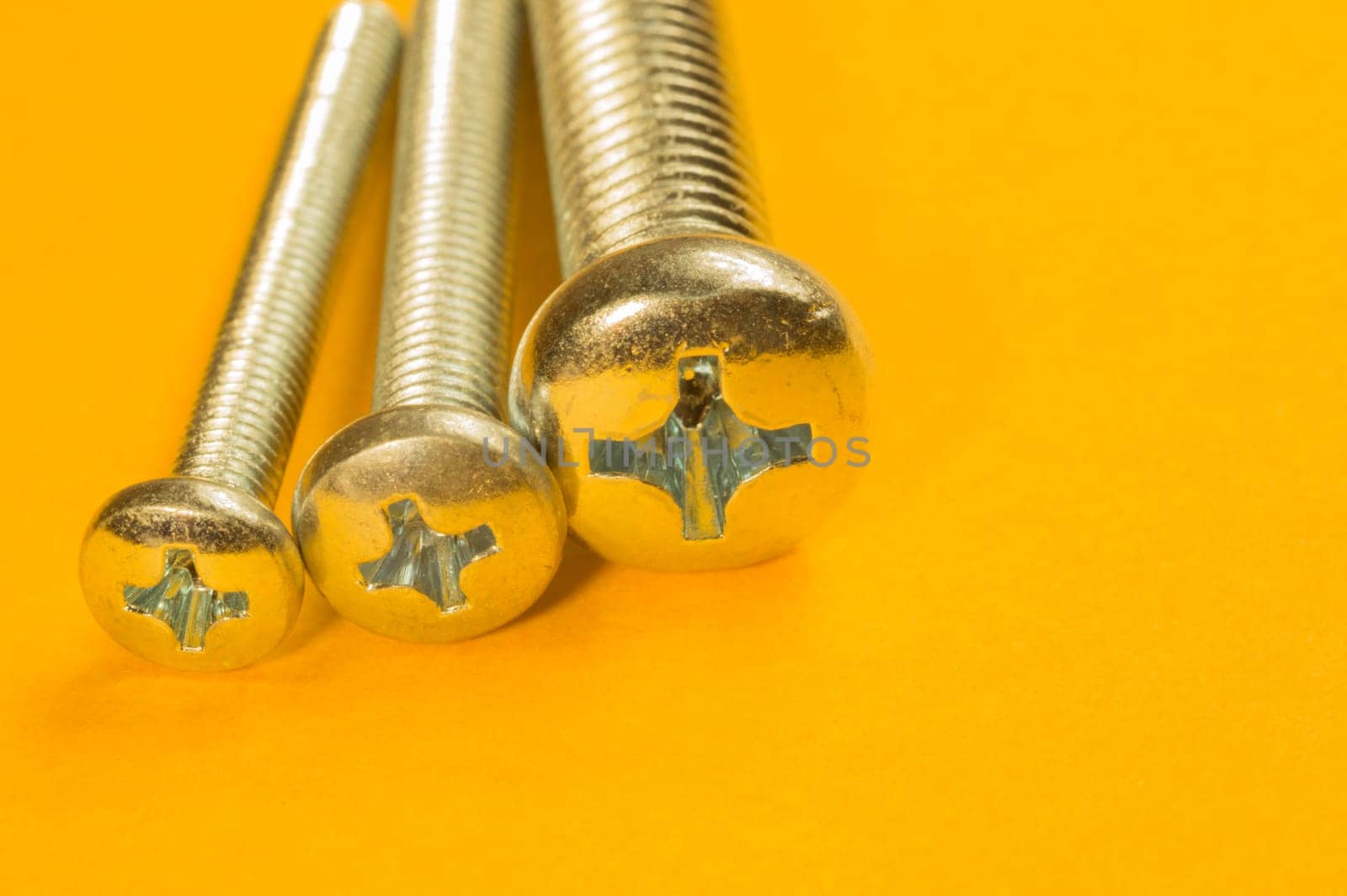 Steel screw on a yellow background. working tools