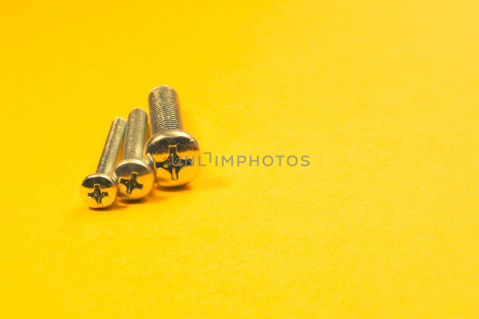 Steel screw on a yellow background. working tools