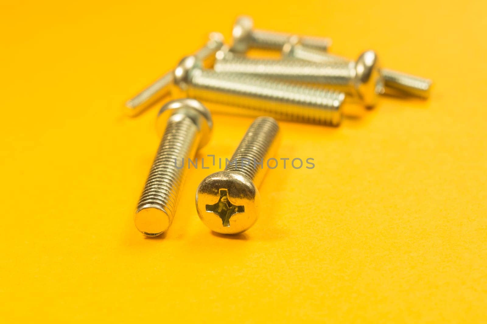 Steel screw on a yellow background. working tools