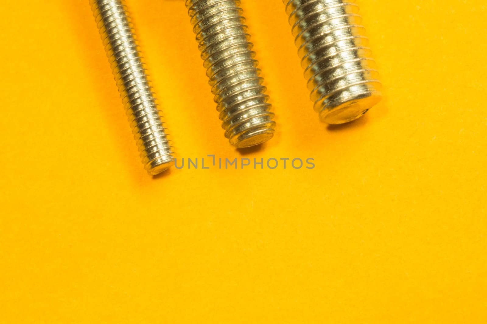 Steel screw on a yellow background. working tools