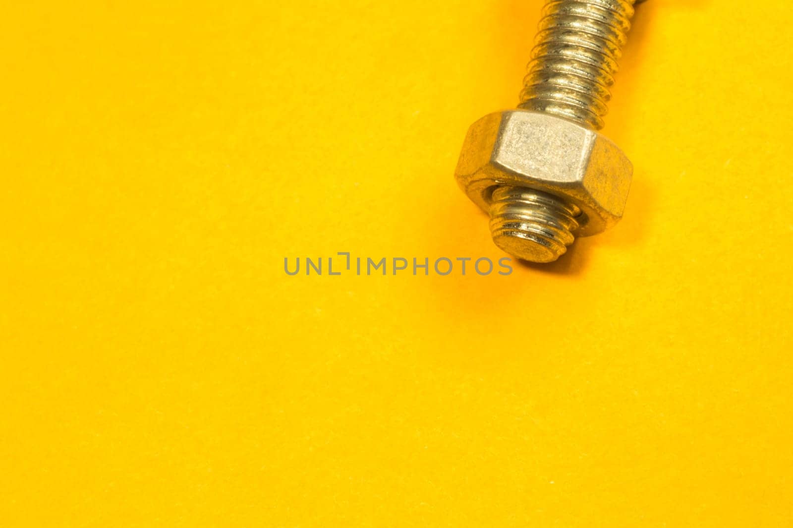 Steel screw on a yellow background. working tools