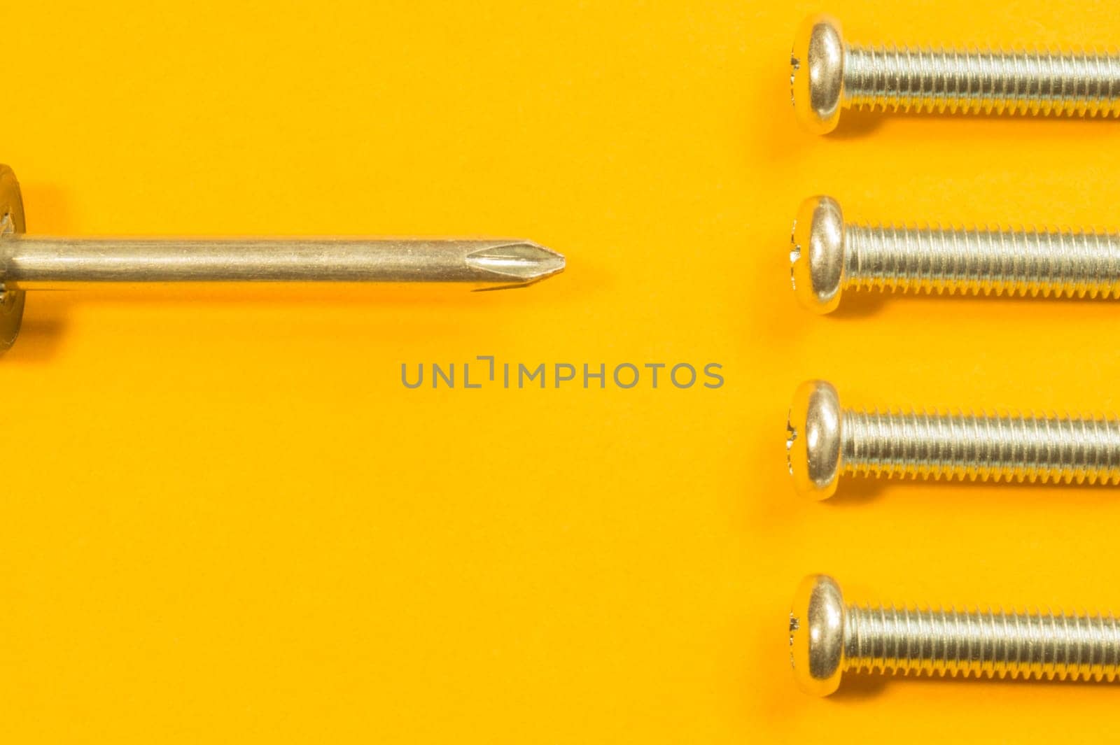 Steel screw on a yellow background. working tools