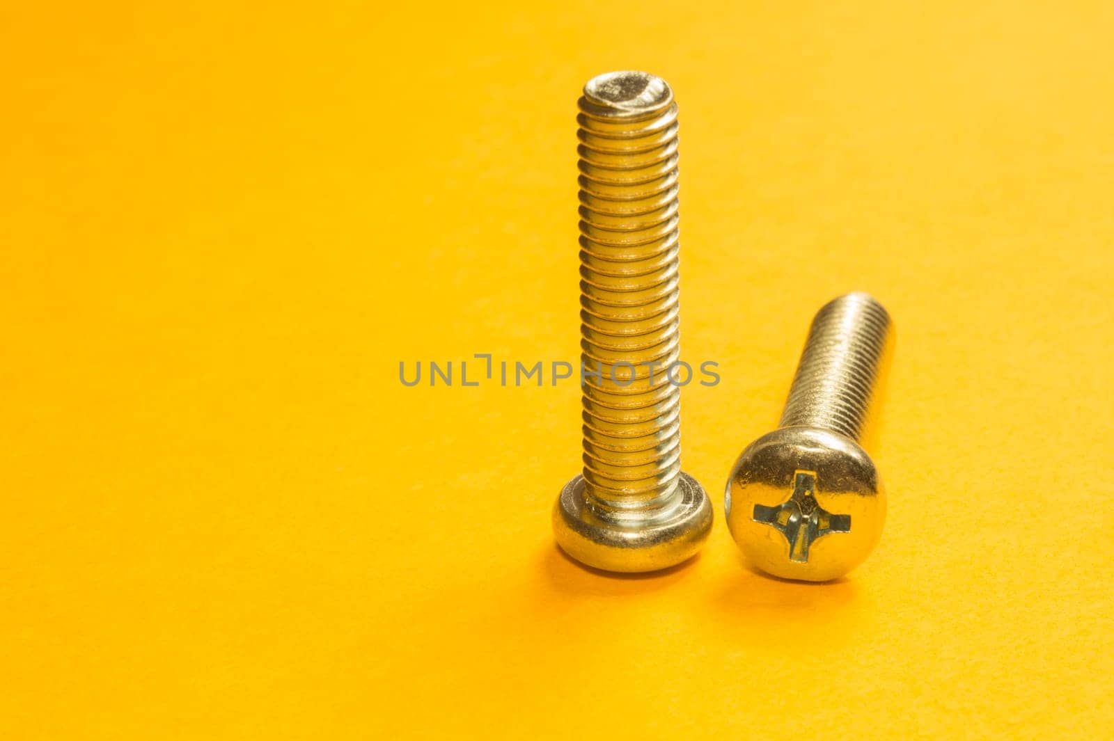 Steel screw on a yellow background. working tools