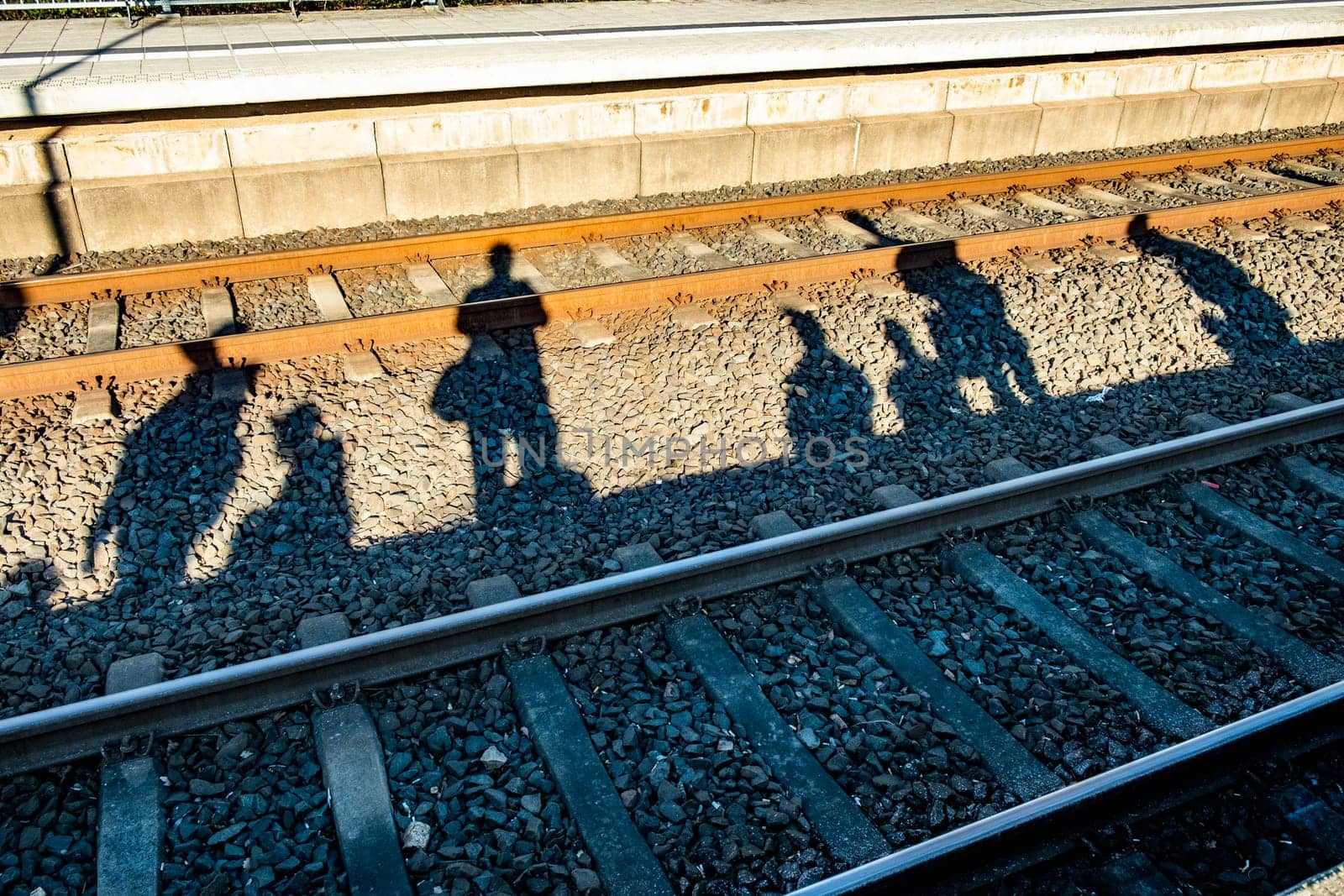 shadow of people waiting for the train with rails