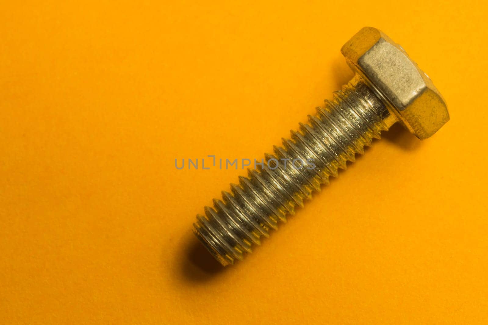 Steel screw on a yellow background. working tools