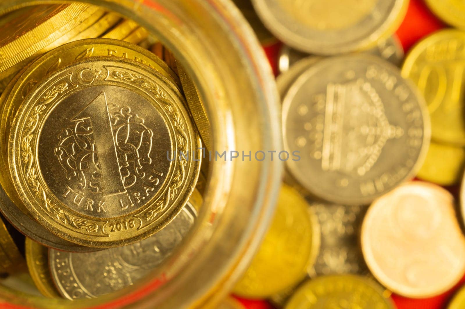 Coins of different countries in a glass jar. a lot of metal coins of different denominations and various countries. financial background. turkish lira in the foreground
