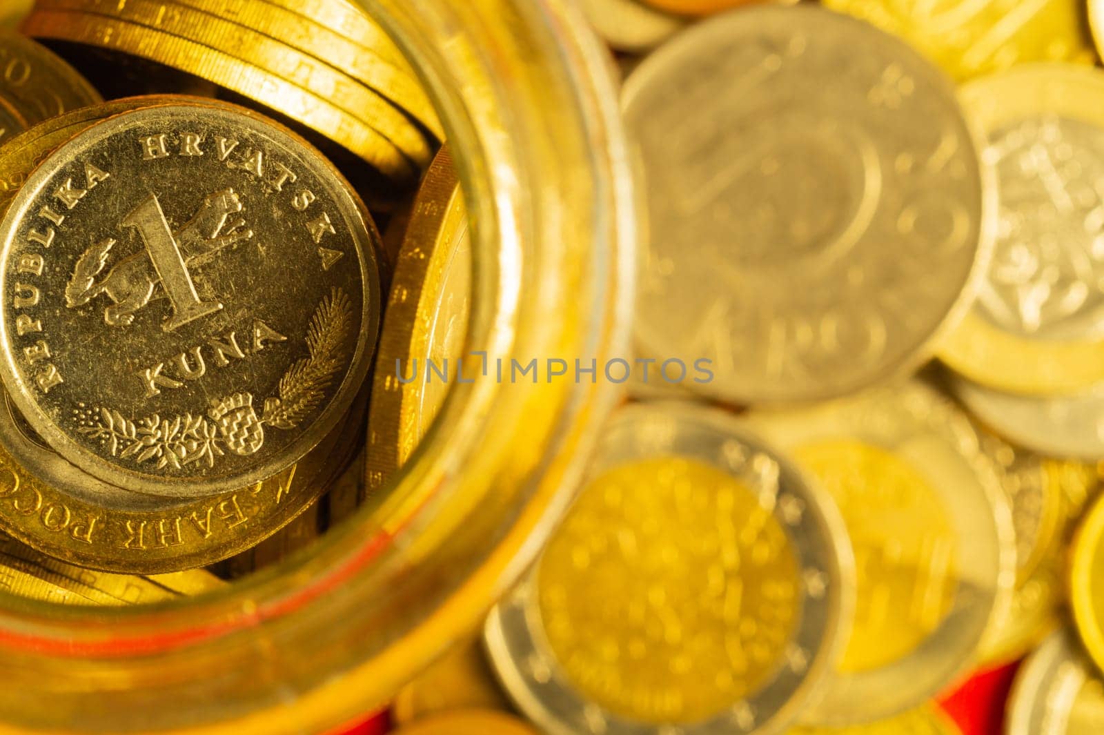 Coins of different countries in a glass jar. a lot of metal coins of different denominations and various countries. financial background. croatian kuna in the foreground