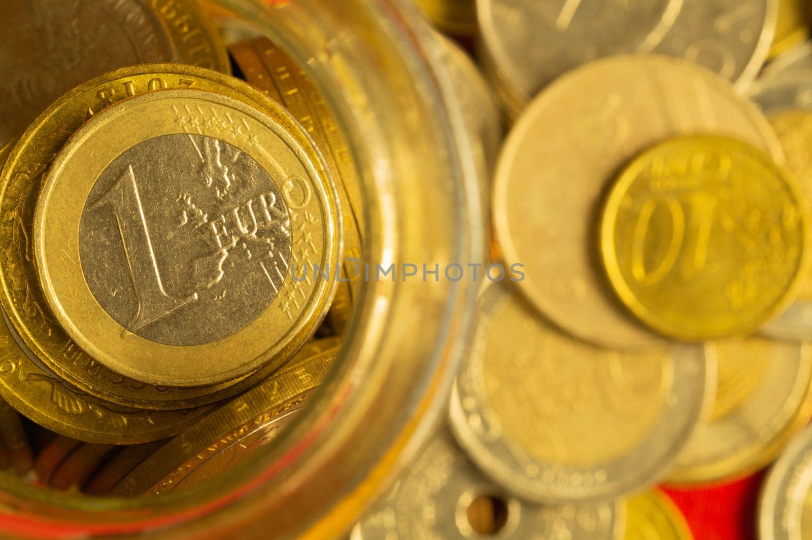 Coins of different countries in a glass jar. a lot of metal coins of different denominations and various countries. financial background. euro coin in the foreground