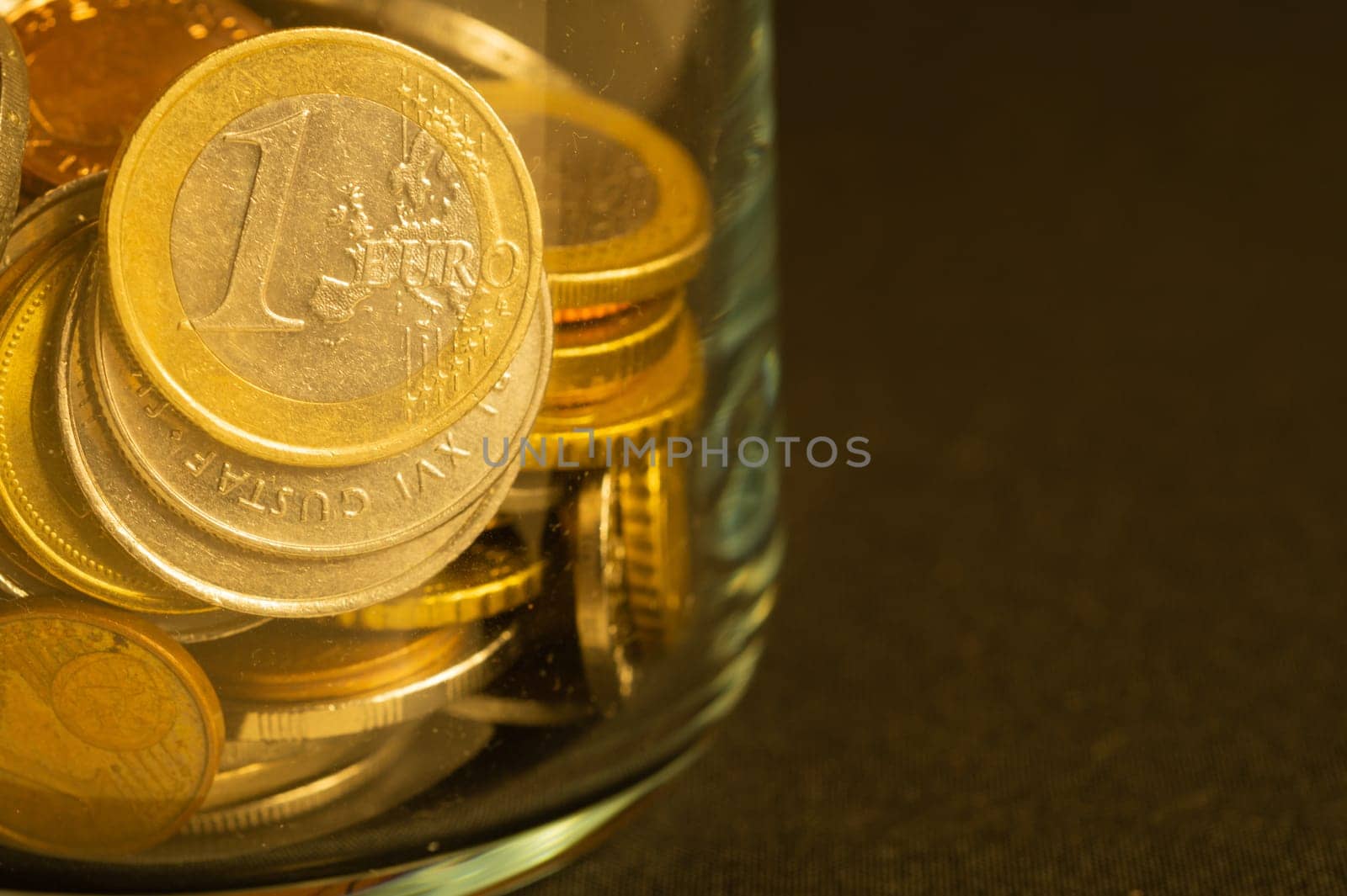 Coins of different countries in a glass jar. a lot of metal coins of different denominations and various countries. financial background. euro coin in the foreground
