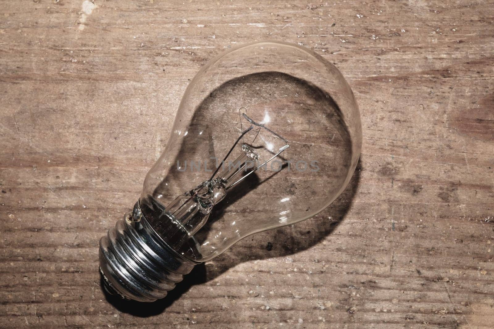 Light bulb on a wooden background. old lamp lies on the table.