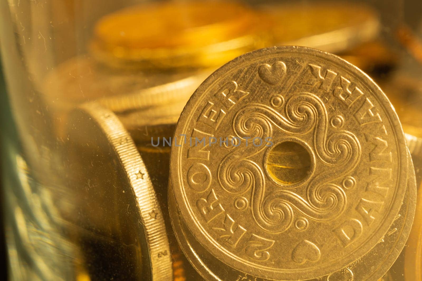 Coins of different countries in a glass jar. a lot of metal coins of different denominations and various countries. financial background. danish krone in the foreground