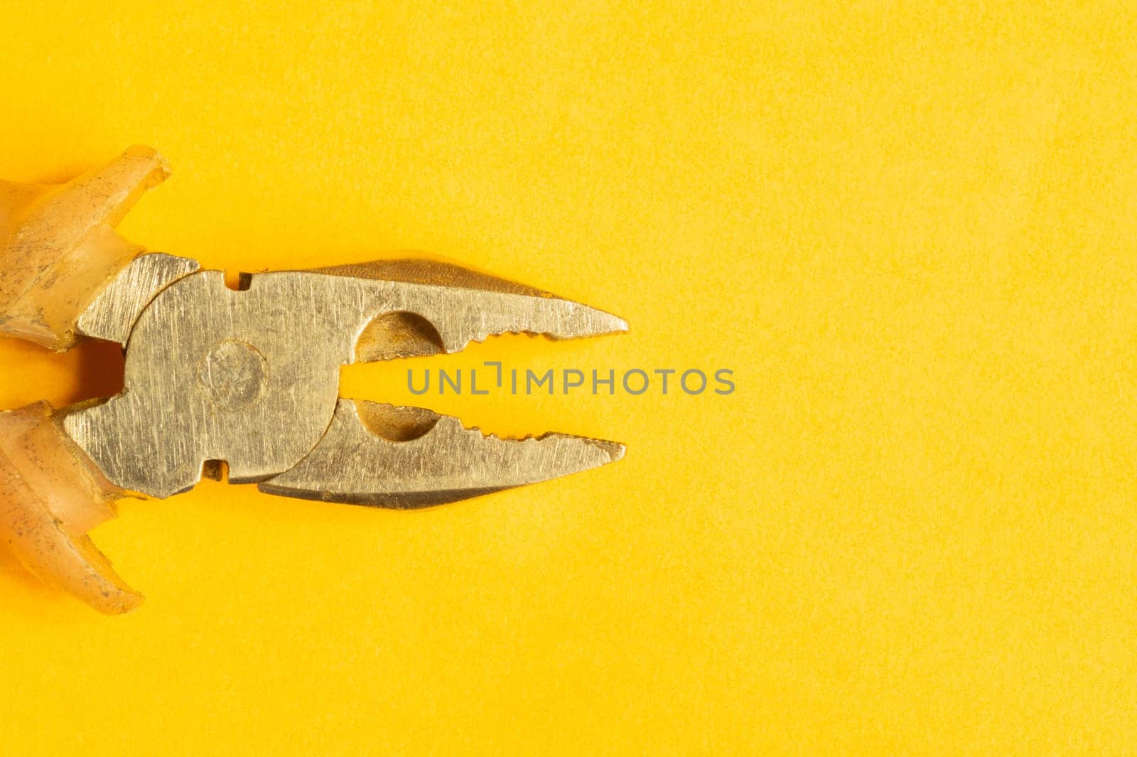 Pliers with orange handles on yellow background. work tool. copy space