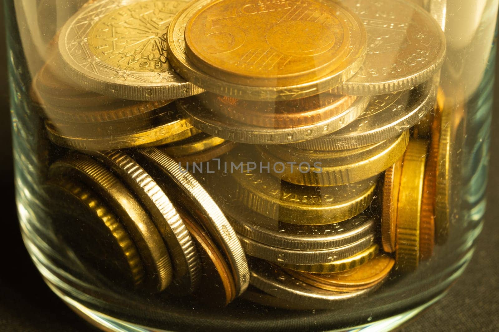 Coins of the different countries in a glass jar. a lot of metal coins of different denominations and various countries. finance background
