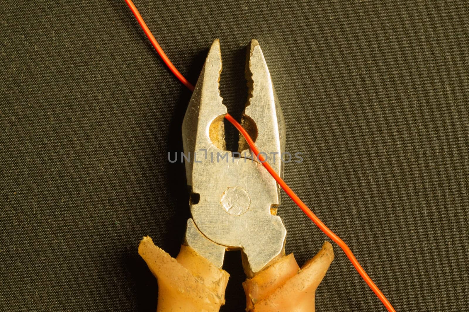 Pliers cuts a red wire on black background. pliers with orange handles. work tool. copy space
