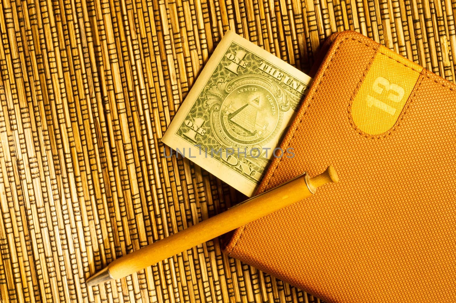 One dollar in a notebook with pen on wooden bamboo background. money as a bookmark. financial background