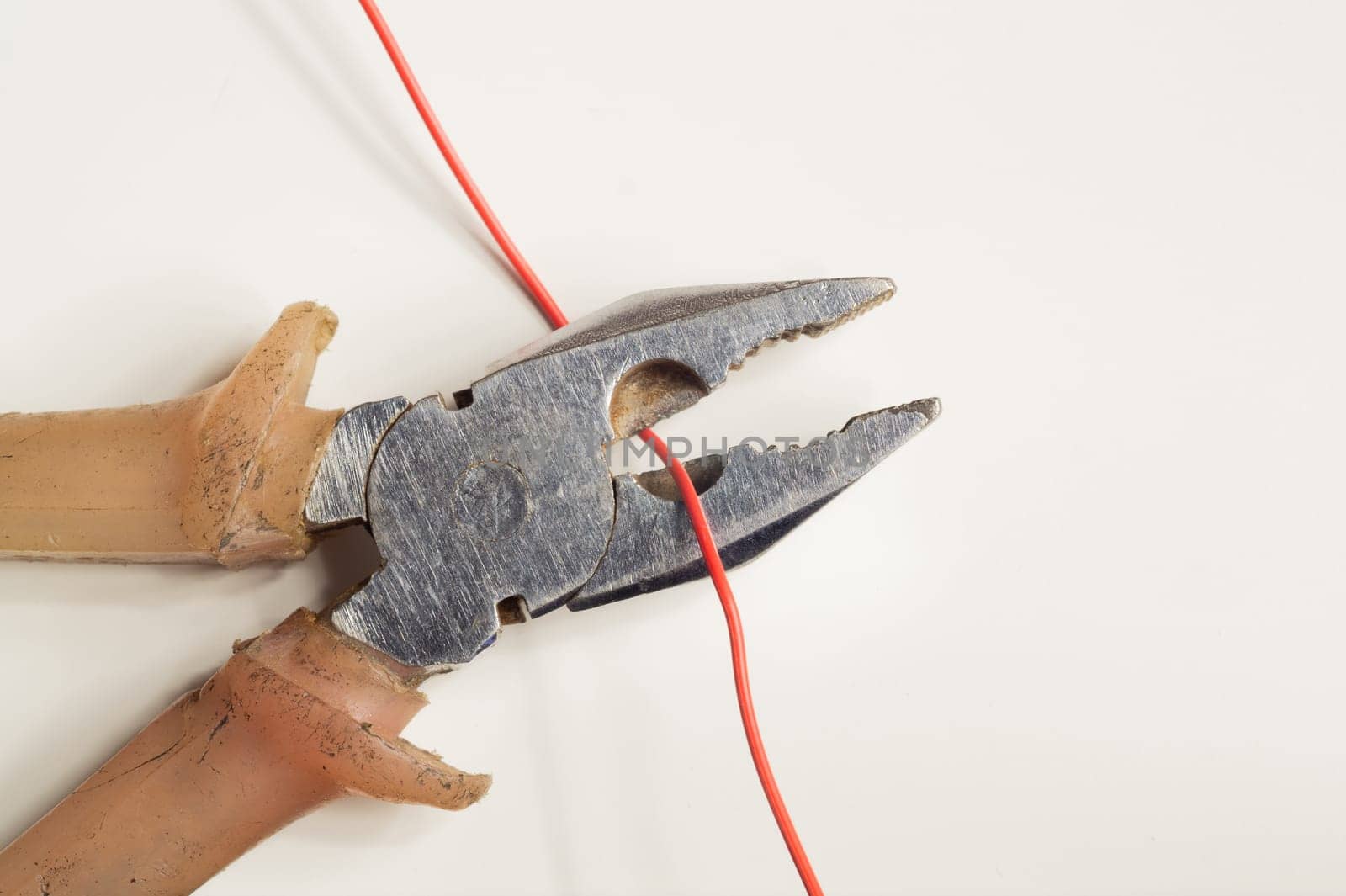Pliers cuts a red wire on white background. work tool. copy space