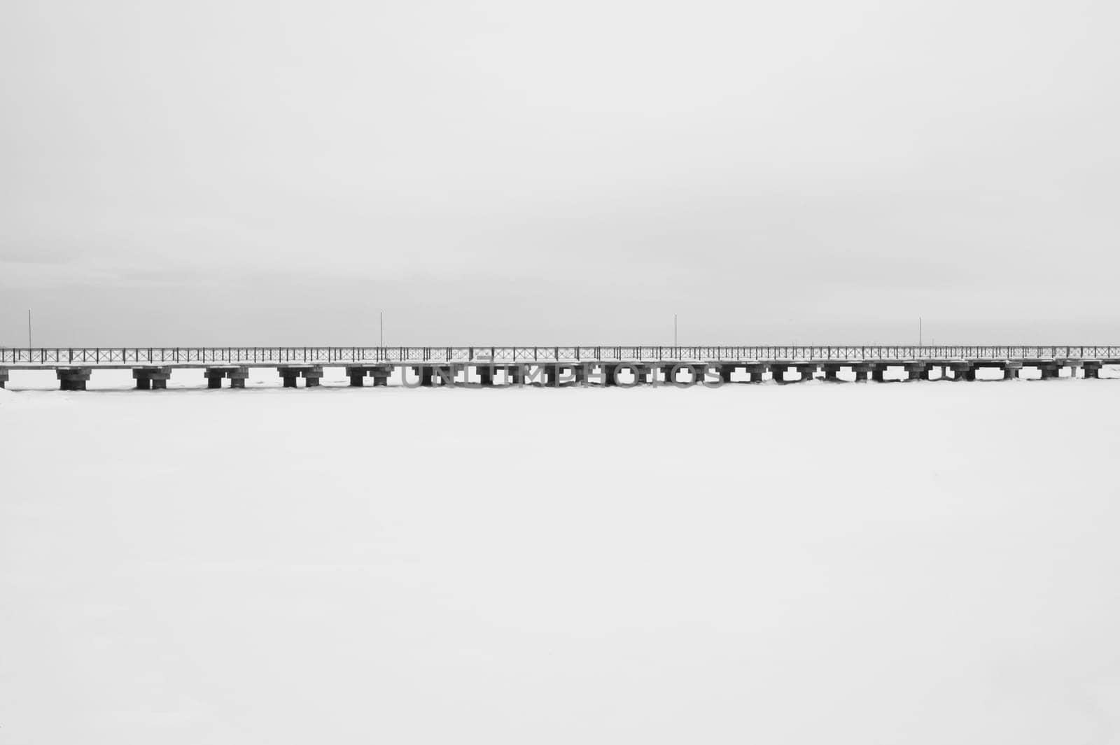 Bridge on the frozen lake. long footbridge dividing the horizon. conceptual minimalistic image. black and white background with copy space