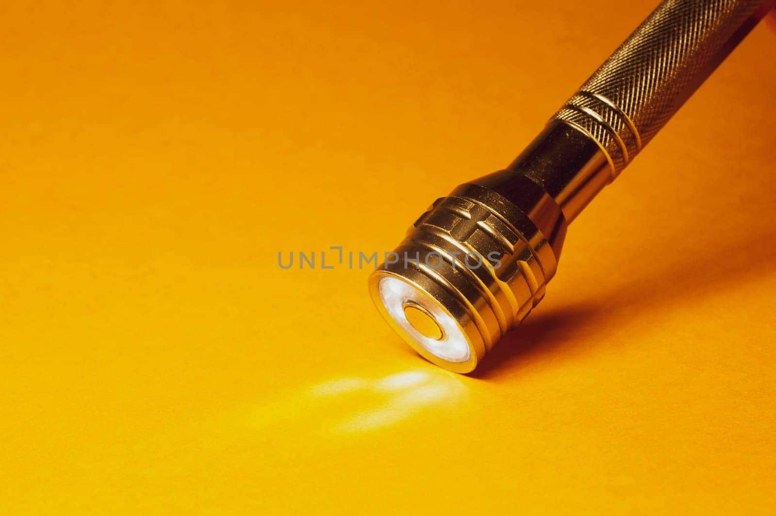 Metal flashlight on a yellow background