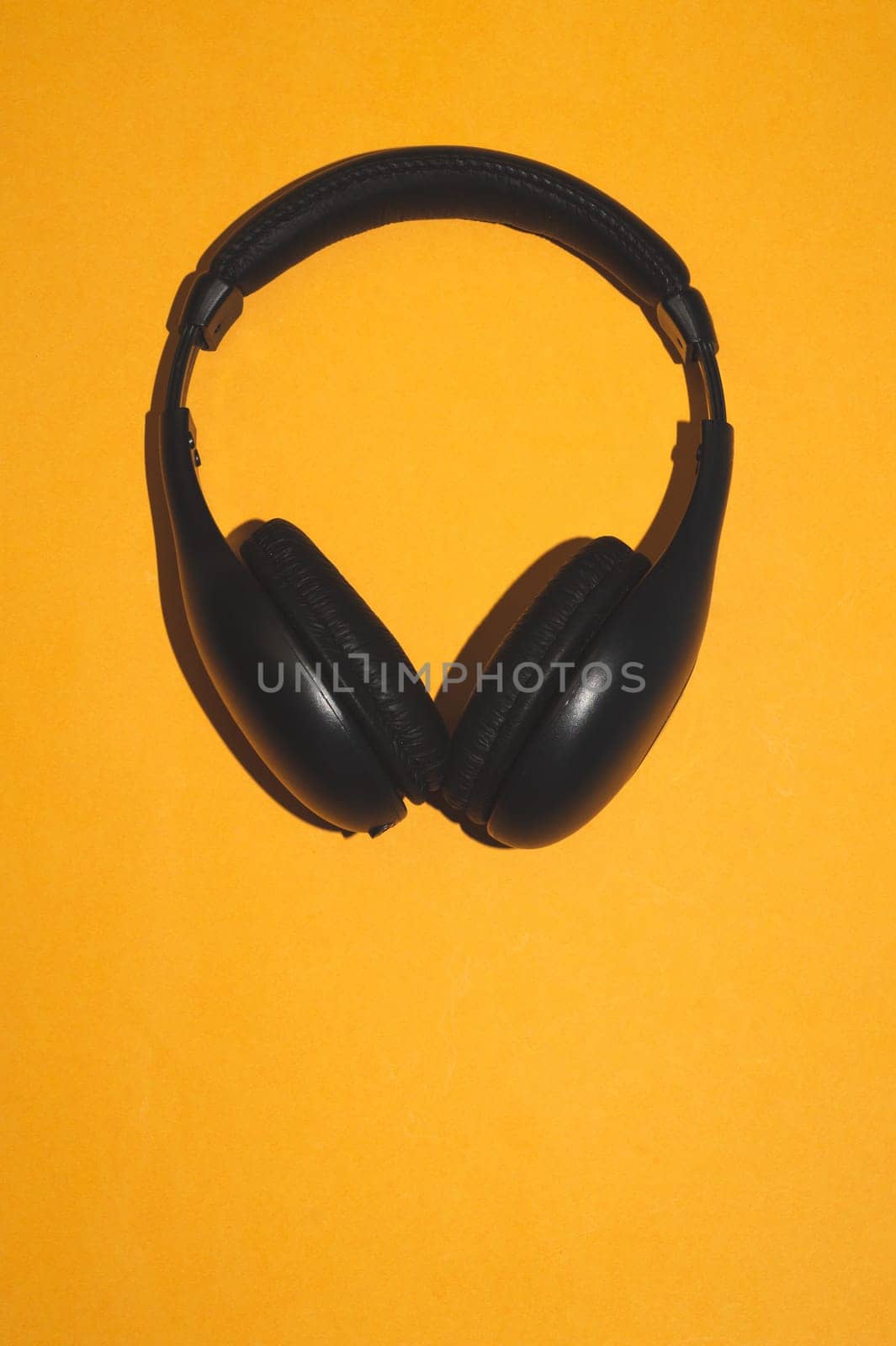 Black headphones on a yellow background. wireless earphones