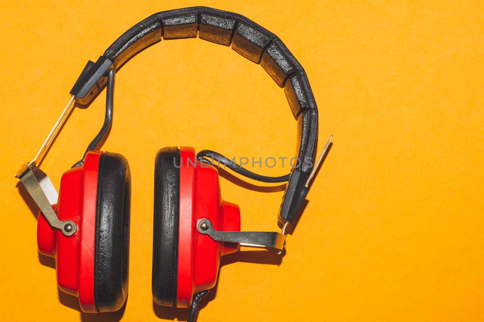 Vintage red headphones on yellow background. retro earphones