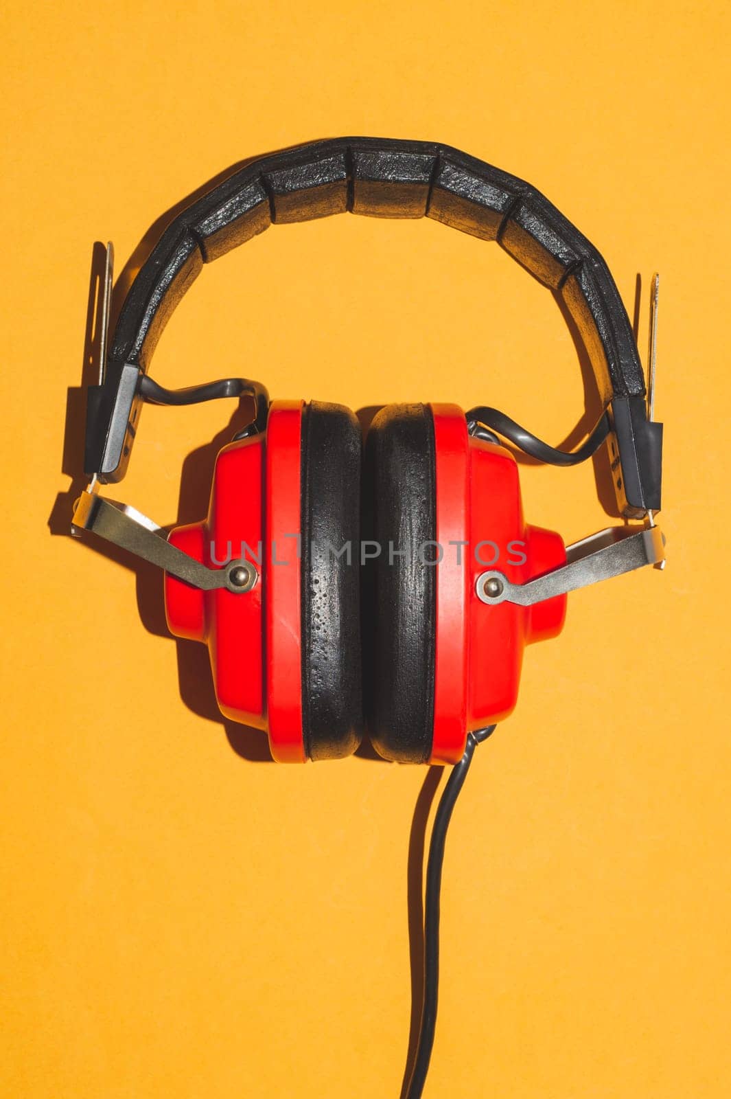 Vintage red headphones on yellow background. retro earphones