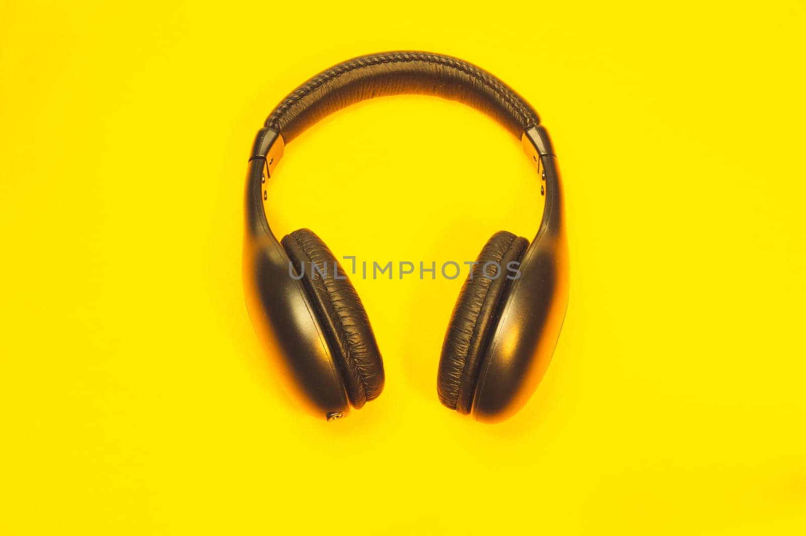 Black headphones on a yellow background. wireless earphones