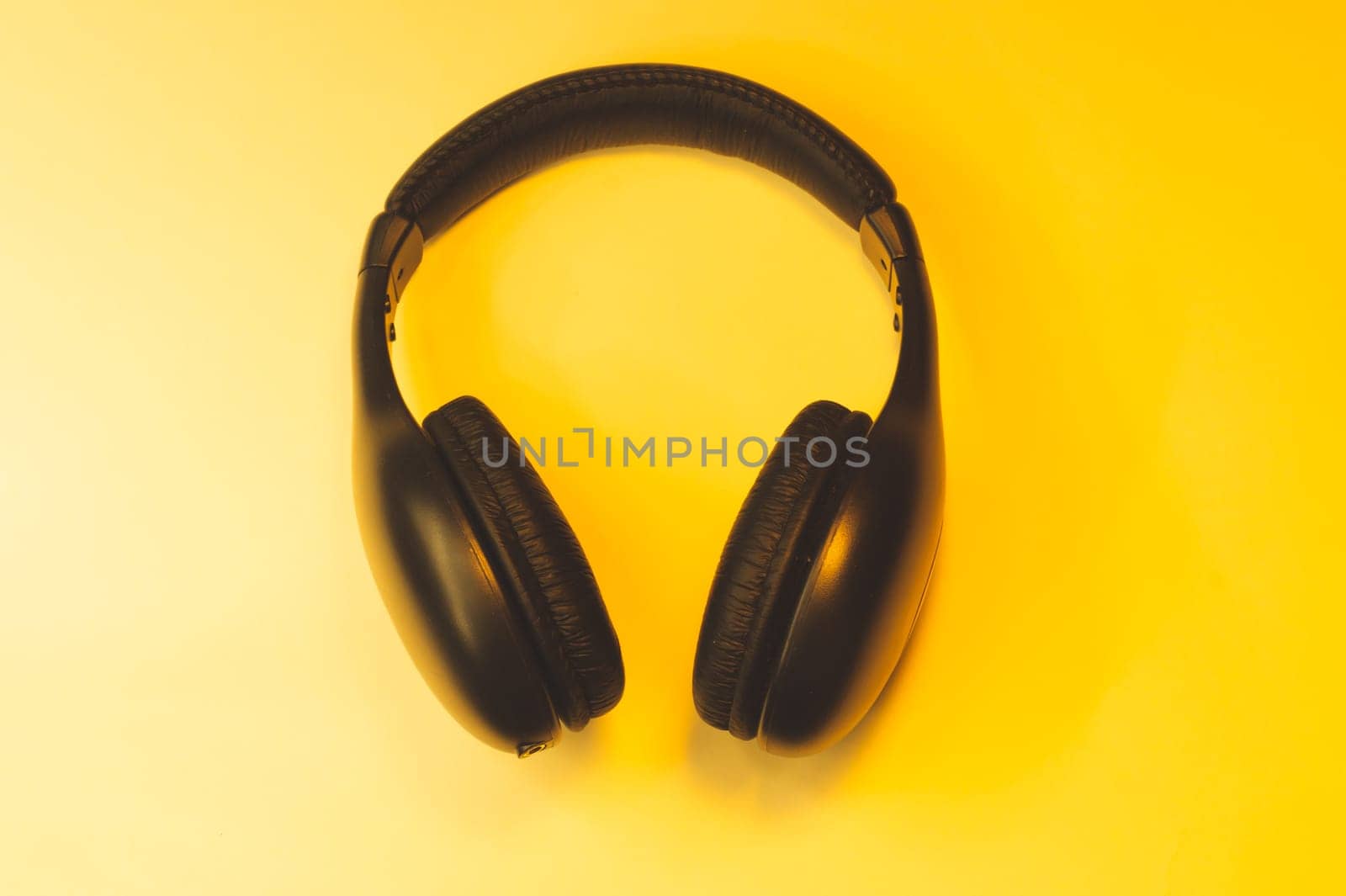 Black headphones on a yellow background. wireless earphones