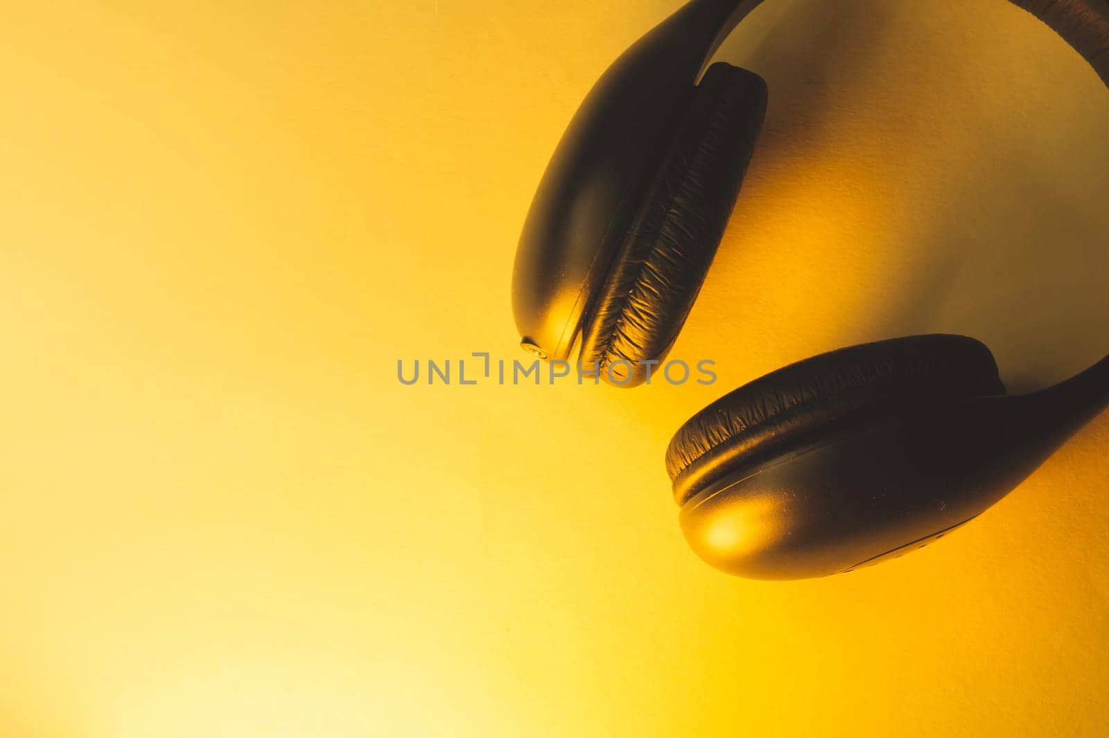 Black headphones on a yellow background. wireless earphones