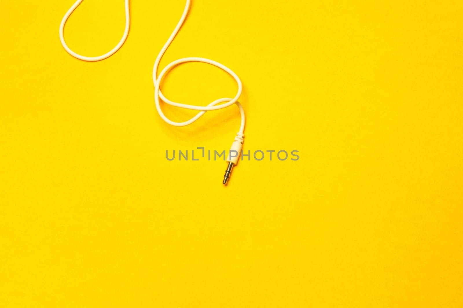 Audio jack with white cable isolated on yellow background