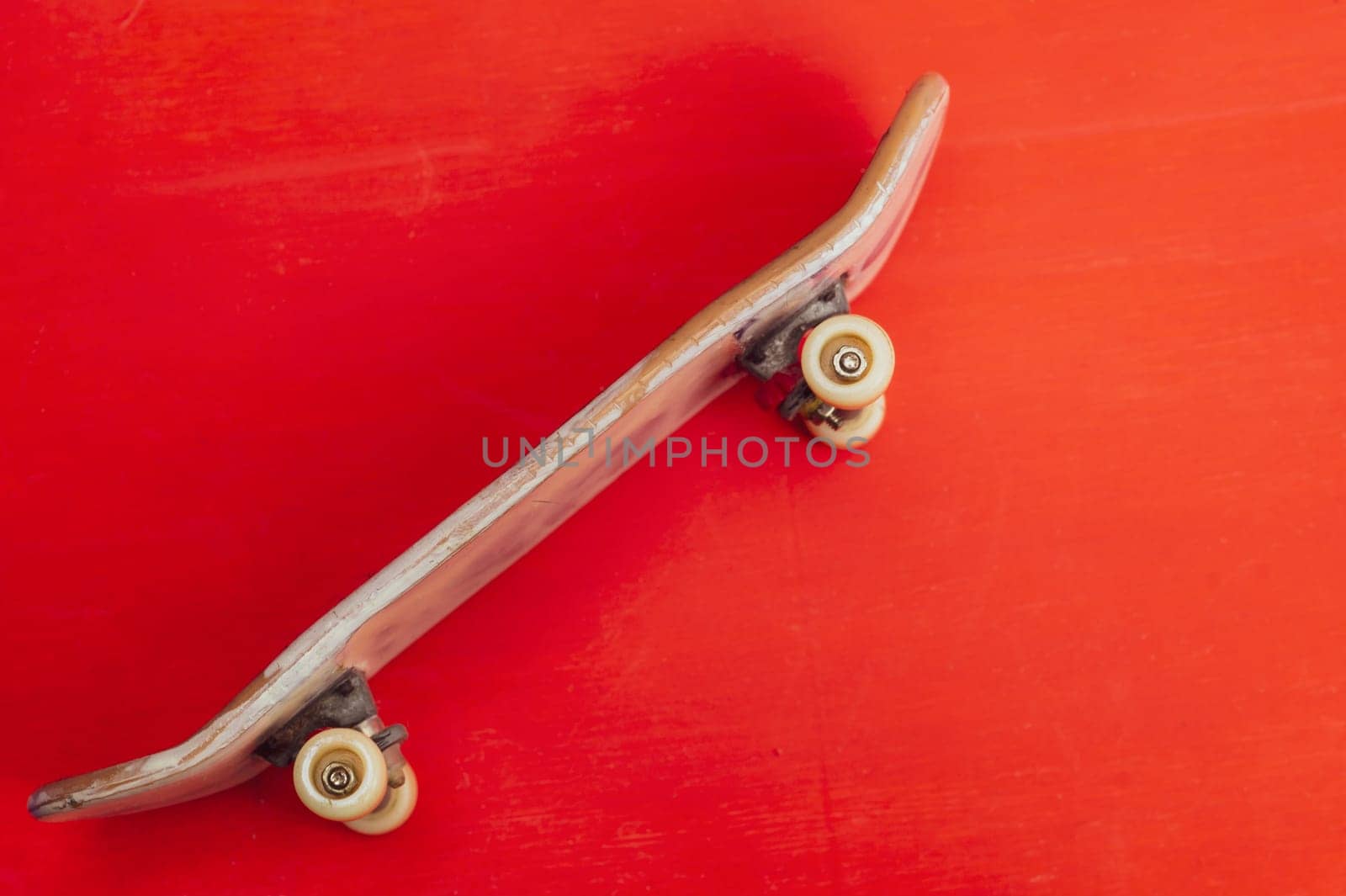 Small skateboard on red background. tiny skate for fingers. fingerboard close up. copy space