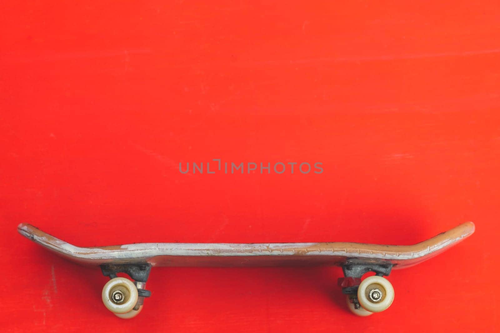 Small skateboard on red background. tiny skate for fingers. fingerboard close up. copy space