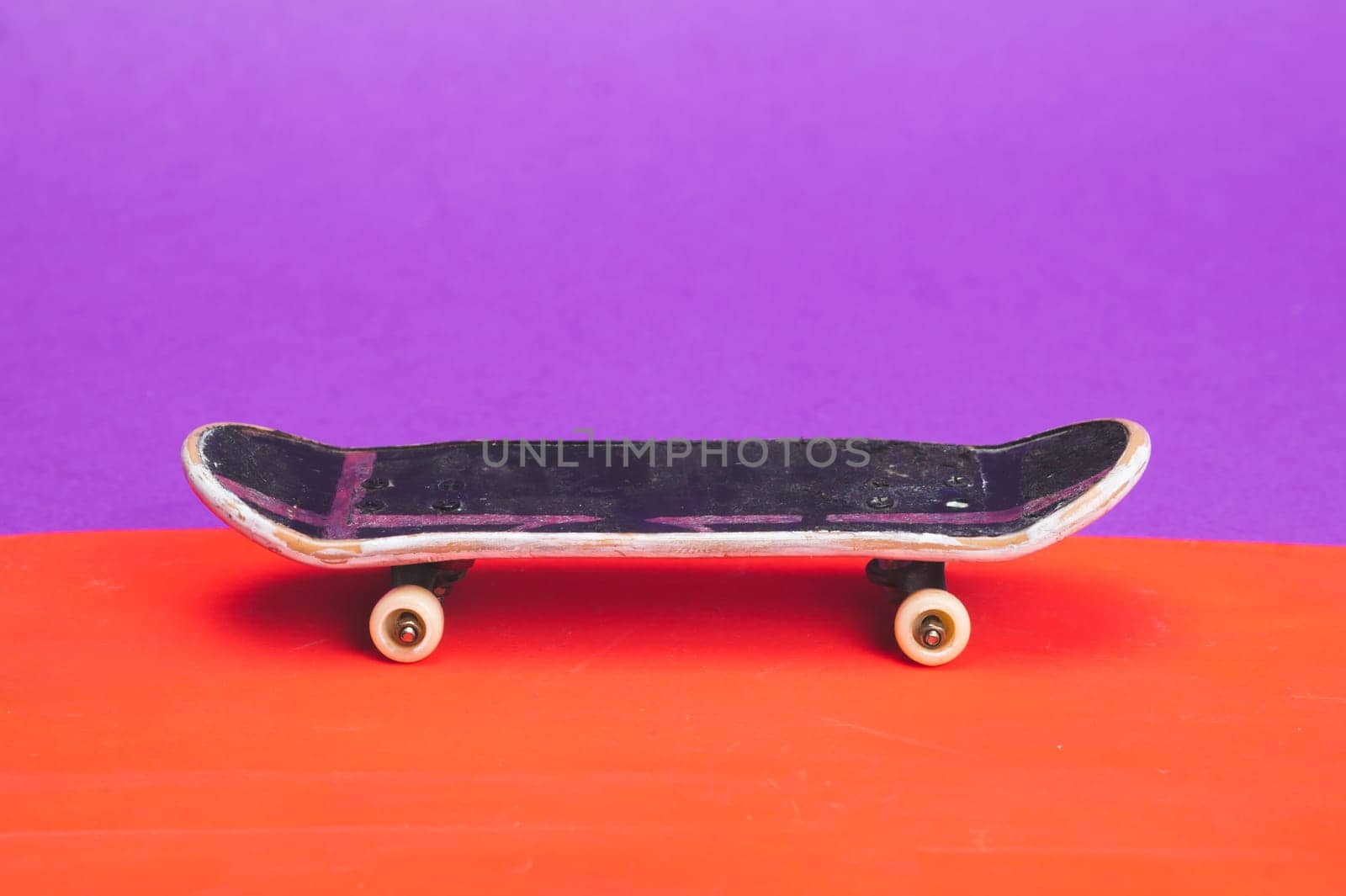 Small skateboard on color background. tiny skate for fingers. fingerboard close up. copy space
