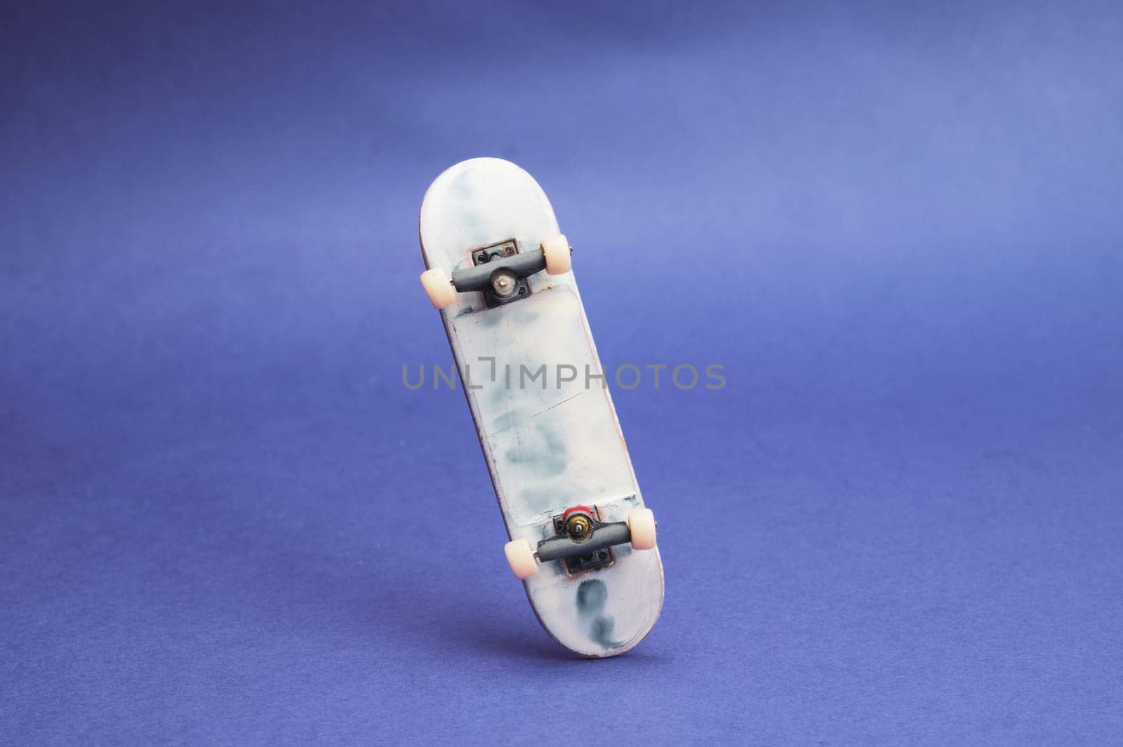 Small skateboard on blue background. tiny skate for fingers. fingerboard close up. home leisure concept. copy space