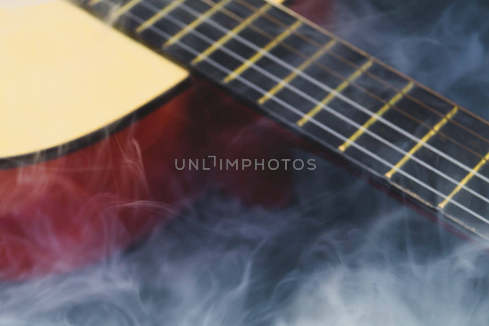 Defocused guitar in smoke abstract background. musical instrument. strings on the guitar fretboard. focus on foreground