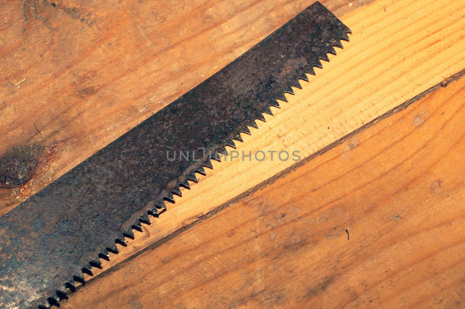 Old hand saw on a dirty wooden background. working area with hand tool. carpentry instrument. manual labor concept