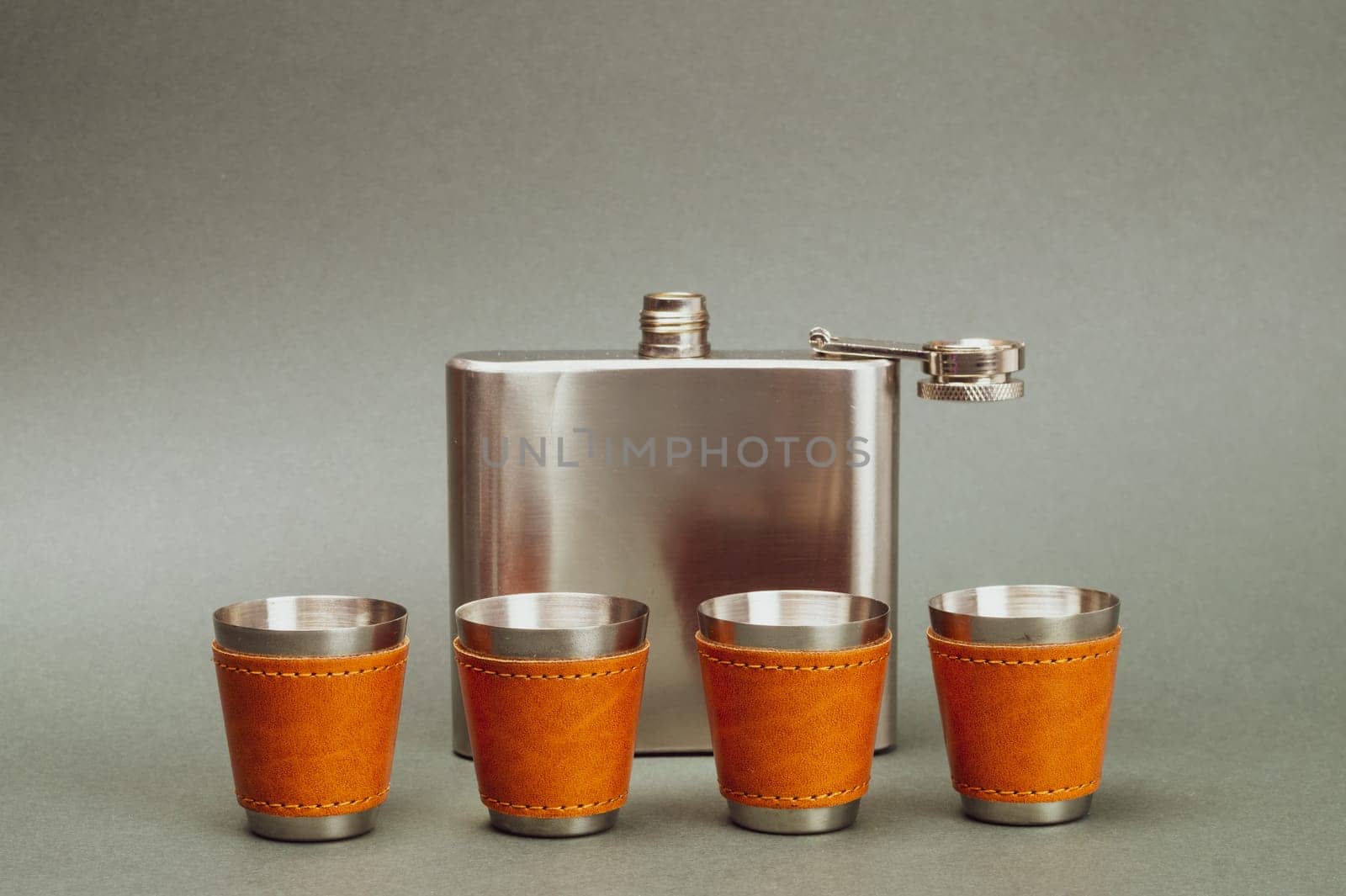 Metallic shot glasses in a row. metal flask. travel shot glass for alcohol with leather casing over the stainless steel. personal accessory set. copy space